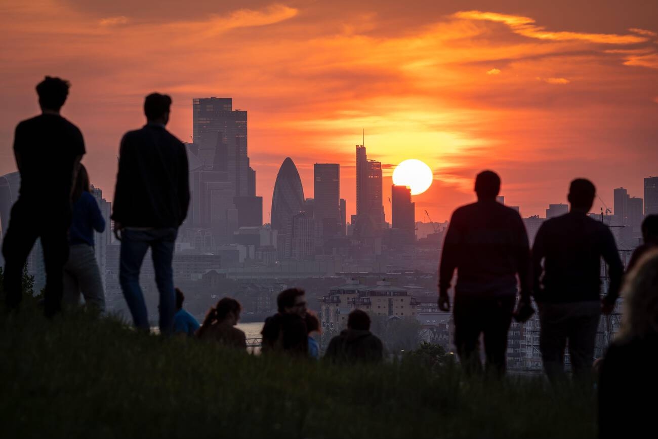 Groups of people watch the sun go down from a hill in London, as a heat health alert coming into place across much of the country