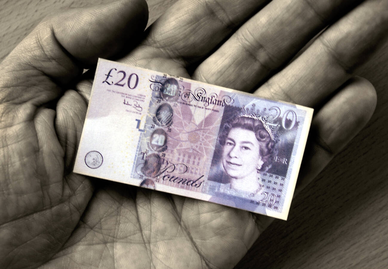 Brexit,Conceptual image of a Shrinking sterling note in the palm of a male hand, depicting UK inflation rate increase, reduced pound,